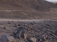 a truck on a dirt road in the desert with rocks and stones on the ground