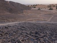 a truck on a dirt road in the desert with rocks and stones on the ground