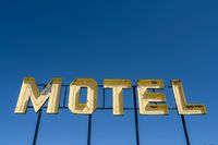 a motel sign sitting up against a blue sky with some clouds in the background of it