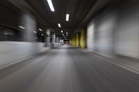 motion blurry of a dark tunnel that leads into a building with a green light