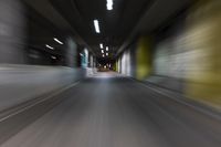 motion blurry of a dark tunnel that leads into a building with a green light