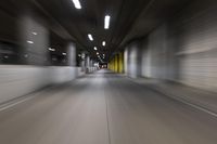 motion blurry of a dark tunnel that leads into a building with a green light