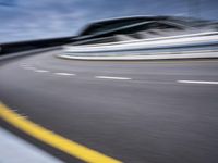 motion blur image of an empty road by buildings with sky background of blurry car coming on it