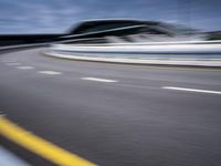 motion blur image of an empty road by buildings with sky background of blurry car coming on it
