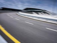 motion blur image of an empty road by buildings with sky background of blurry car coming on it