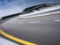motion blur image of an empty road by buildings with sky background of blurry car coming on it