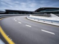 motion blur image of an empty road by buildings with sky background of blurry car coming on it