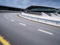 motion blur image of an empty road by buildings with sky background of blurry car coming on it