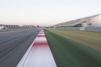 motion blurry photograph of a racing track during the day or night, with green grass, gravel and red stripes on the bottom