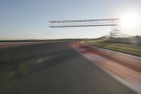 motion blurs down an airport runway and overhang the landing strip at sunrise with some clouds