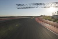 motion blurs down an airport runway and overhang the landing strip at sunrise with some clouds