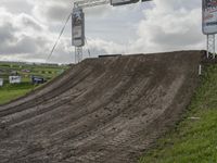 a dirt bike rider goes up a hill, making a big jump in a race track