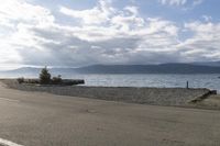 there is a motor bike parked along the beach near a small boat ramp and mountains on the side