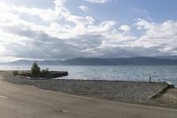 there is a motor bike parked along the beach near a small boat ramp and mountains on the side