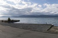 there is a motor bike parked along the beach near a small boat ramp and mountains on the side