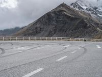 a motorbike driving down a winding mountain road with a view of snow capped mountains