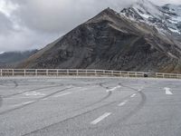 a motorbike driving down a winding mountain road with a view of snow capped mountains