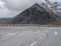 a motorbike driving down a winding mountain road with a view of snow capped mountains