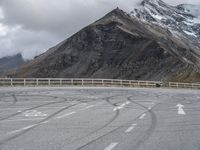 a motorbike driving down a winding mountain road with a view of snow capped mountains