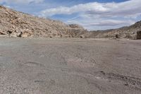 a motorcycle is parked on the desert road in front of a mountain range and a rocky landscape