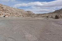 a motorcycle is parked on the desert road in front of a mountain range and a rocky landscape