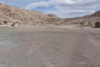 a motorcycle is parked on the desert road in front of a mountain range and a rocky landscape