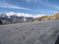 the man is riding his motorcycle along the dirt road in the mountains on a sunny day