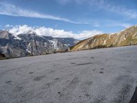 the man is riding his motorcycle along the dirt road in the mountains on a sunny day