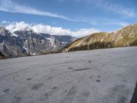 the man is riding his motorcycle along the dirt road in the mountains on a sunny day