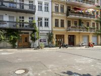 a motorcycle is driving along a city street near large buildings and gardens and greenery