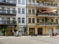 a motorcycle is driving along a city street near large buildings and gardens and greenery