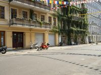 a motorcycle is driving along a city street near large buildings and gardens and greenery