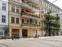 a motorcycle is driving along a city street near large buildings and gardens and greenery