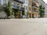 a motorcycle is driving along a city street near large buildings and gardens and greenery