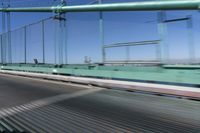a person driving a motorcycle on a bridge on a blue day, the blurry bridge is in the background