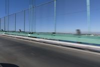 a person driving a motorcycle on a bridge on a blue day, the blurry bridge is in the background