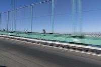a person driving a motorcycle on a bridge on a blue day, the blurry bridge is in the background