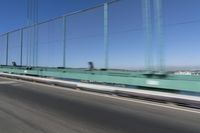 a person driving a motorcycle on a bridge on a blue day, the blurry bridge is in the background