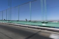 a person driving a motorcycle on a bridge on a blue day, the blurry bridge is in the background