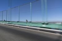 a person driving a motorcycle on a bridge on a blue day, the blurry bridge is in the background