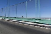 a person driving a motorcycle on a bridge on a blue day, the blurry bridge is in the background