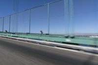 a person driving a motorcycle on a bridge on a blue day, the blurry bridge is in the background