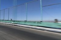 a person driving a motorcycle on a bridge on a blue day, the blurry bridge is in the background