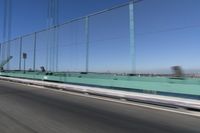 a person driving a motorcycle on a bridge on a blue day, the blurry bridge is in the background