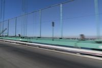 a person driving a motorcycle on a bridge on a blue day, the blurry bridge is in the background