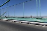 a person driving a motorcycle on a bridge on a blue day, the blurry bridge is in the background