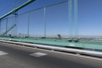 a person driving a motorcycle on a bridge on a blue day, the blurry bridge is in the background