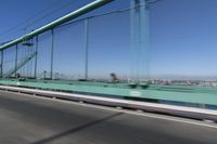 a person driving a motorcycle on a bridge on a blue day, the blurry bridge is in the background