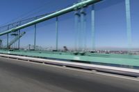 a person driving a motorcycle on a bridge on a blue day, the blurry bridge is in the background