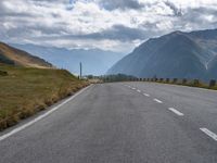 a motorcycle driving along a curvy country side road in front of a mountain range